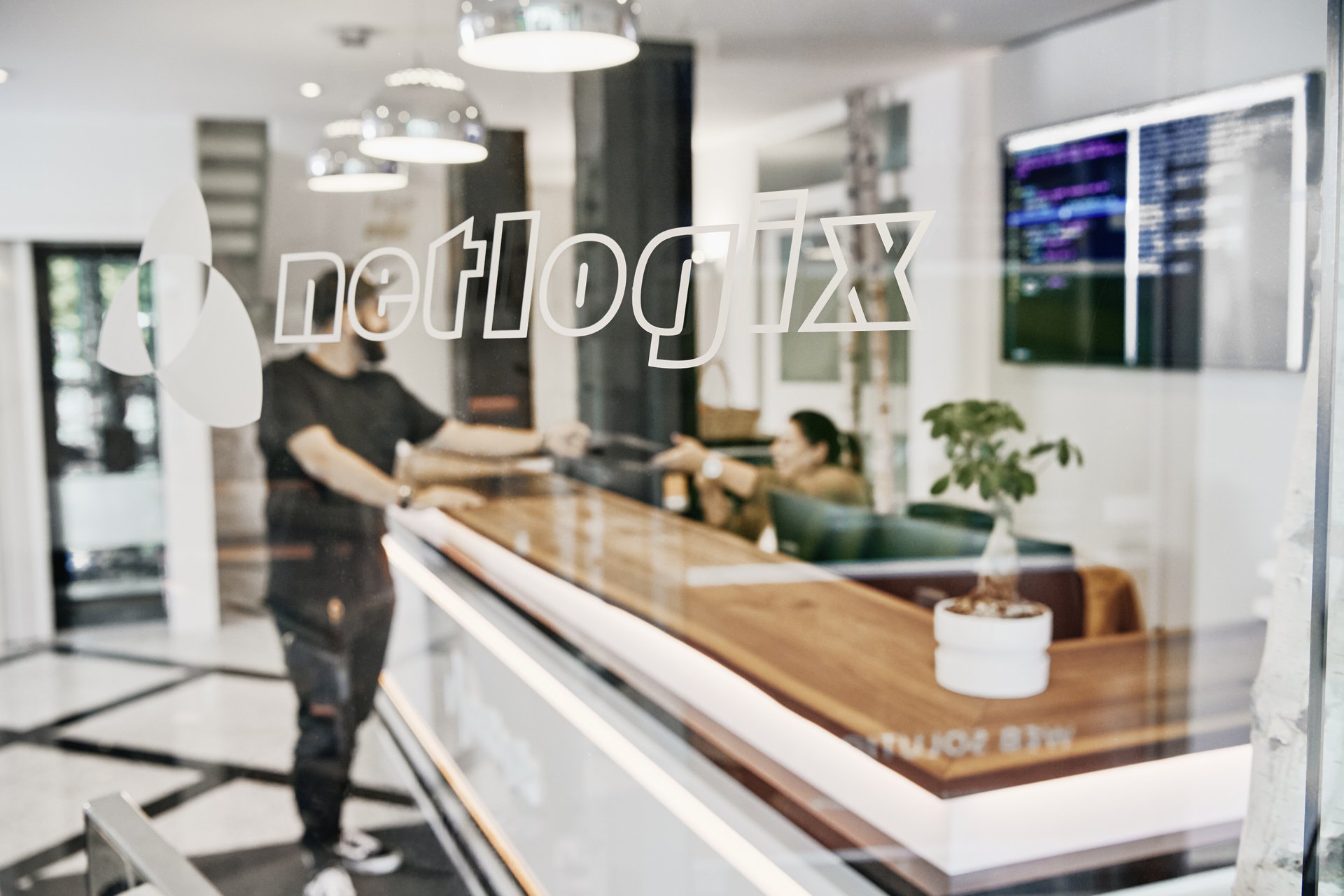 Empfangsbereich der netlogix GmbH & Co. KG mit Logo auf Glas und Beratungsszene